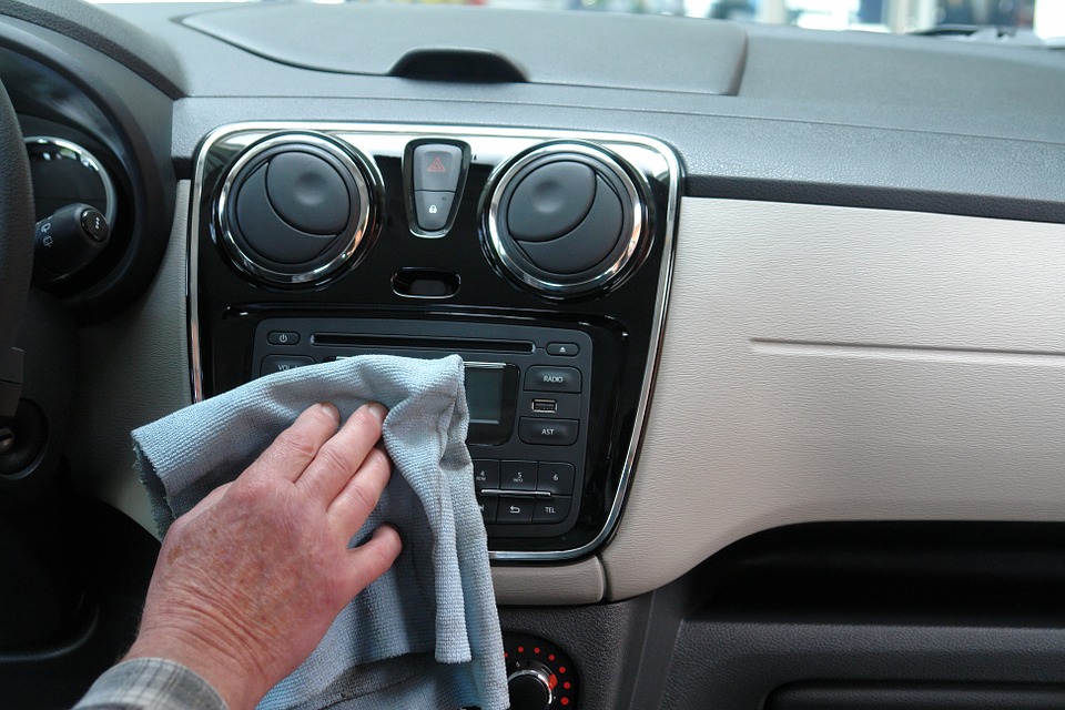 A person cleaning their car dashboard with a cloth