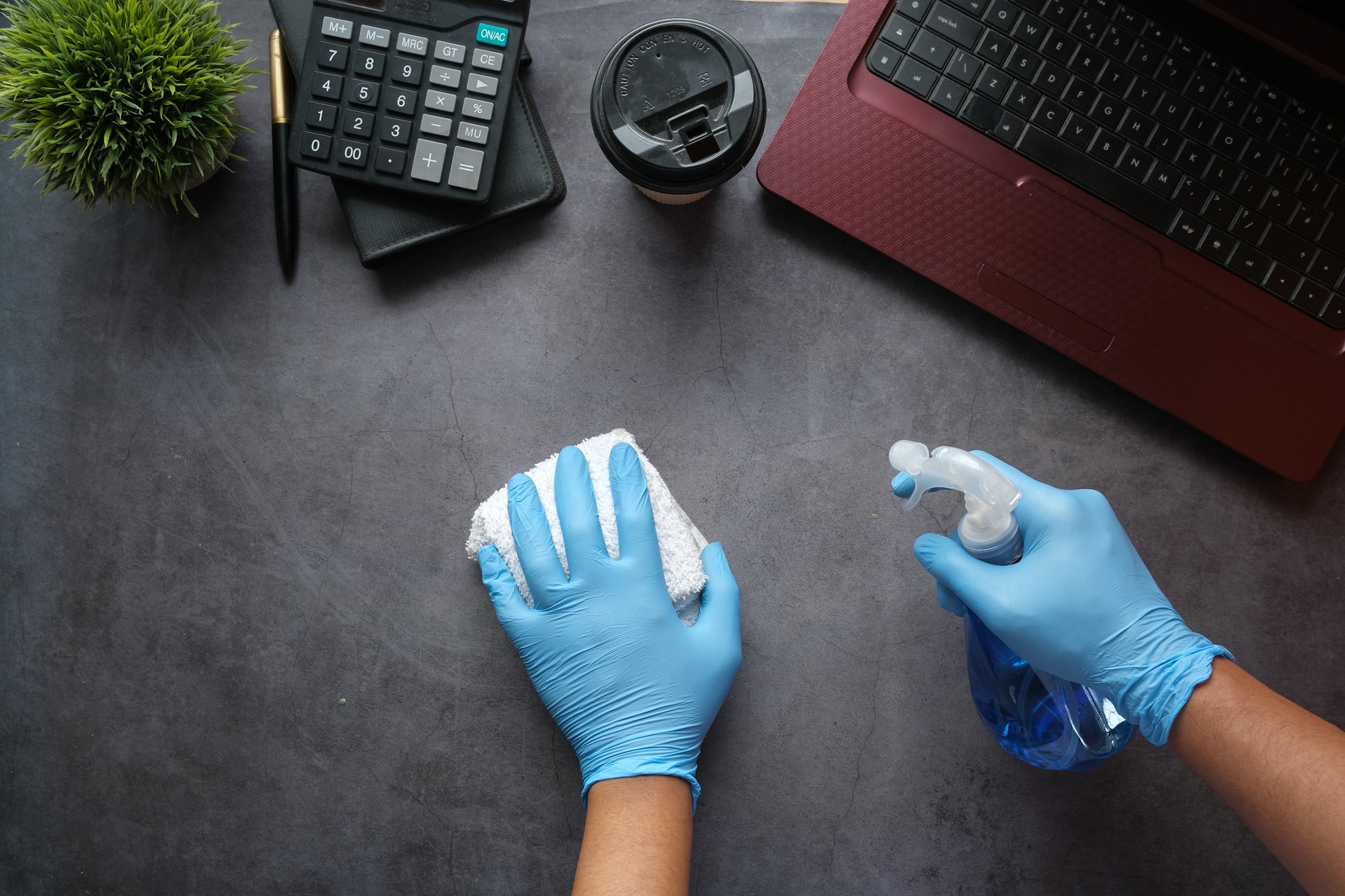 Person wearing blue nitrile gloves washing with a cloth and spray bottl