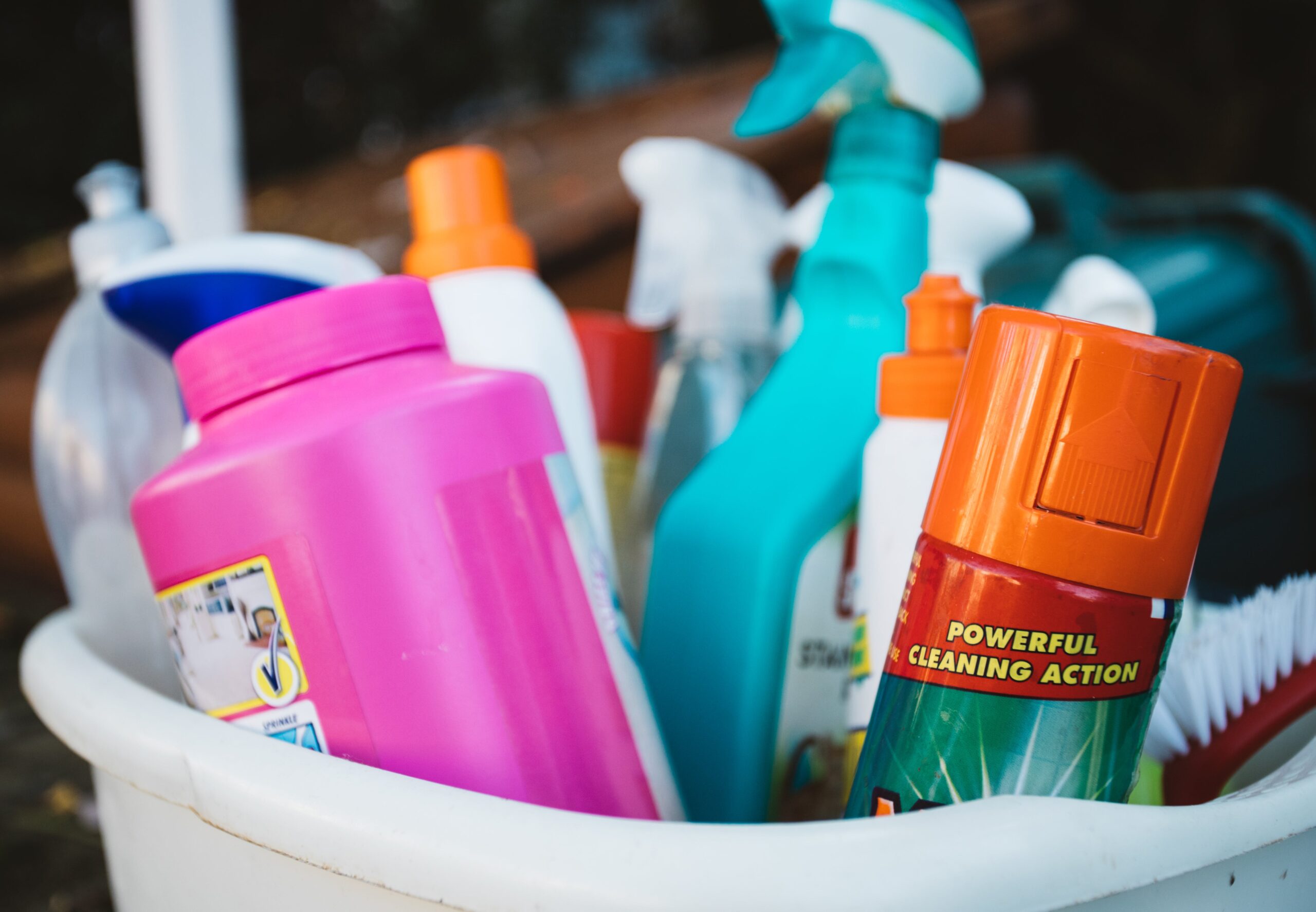 A close up of a plastic tub full of cleaning supplies